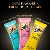 Three Sheba cat treat packages in blue, pink, and yellow on a dark background with text indicating flavors.