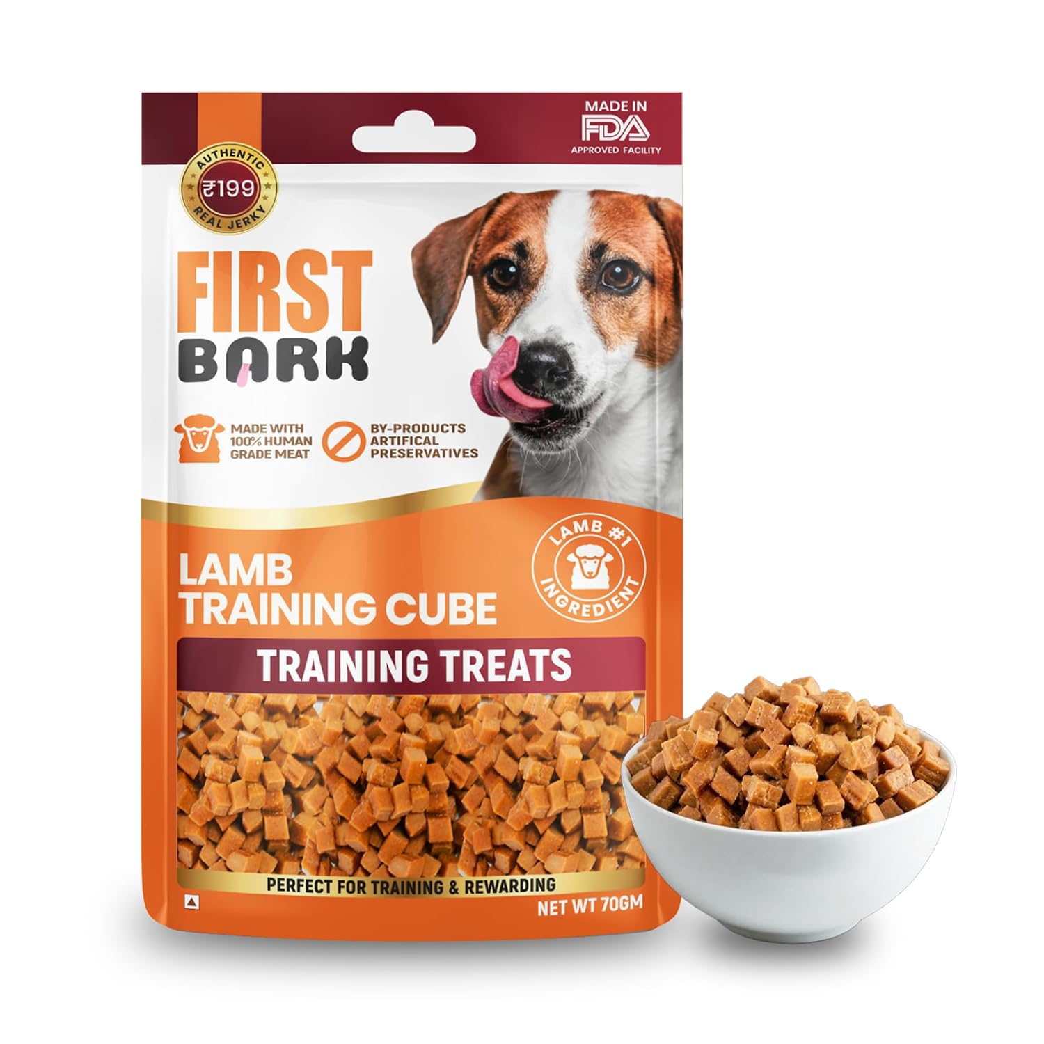 A bag of First Bark Lamb Training Cube treats stands on a white background next to a white bowl filled with the cube-shaped dog treats. The packaging features a brown and white dog photo and orange and maroon panels.