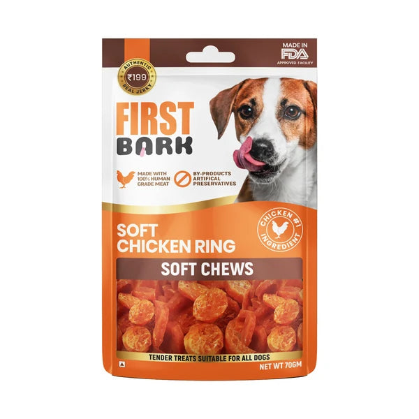 A package of First Bark Soft Chicken Ring Soft Chews dog treats, featuring a brown and orange bag with a photo of a dog on the front and a clear window showing the orange chews inside.