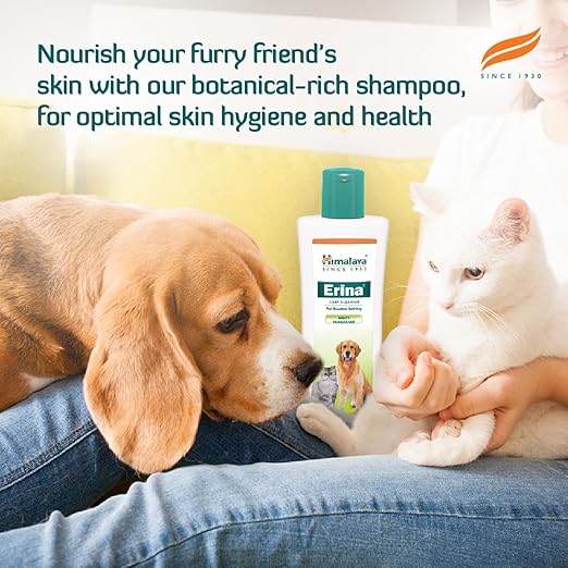 Dog and cat with a bottle of Himalaya Erina shampoo on a couch, promoting botanical-rich shampoo for pets.