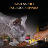 Cat eating from a plate with a small sachet held above it, on a dark background.