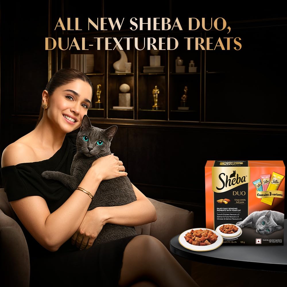 Woman holding a cat with Sheba Duo treats packaging in the background