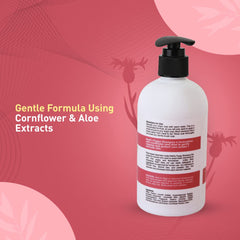 Shampoo bottle with pump on a pink background, featuring text about cornflower and aloe extracts.
